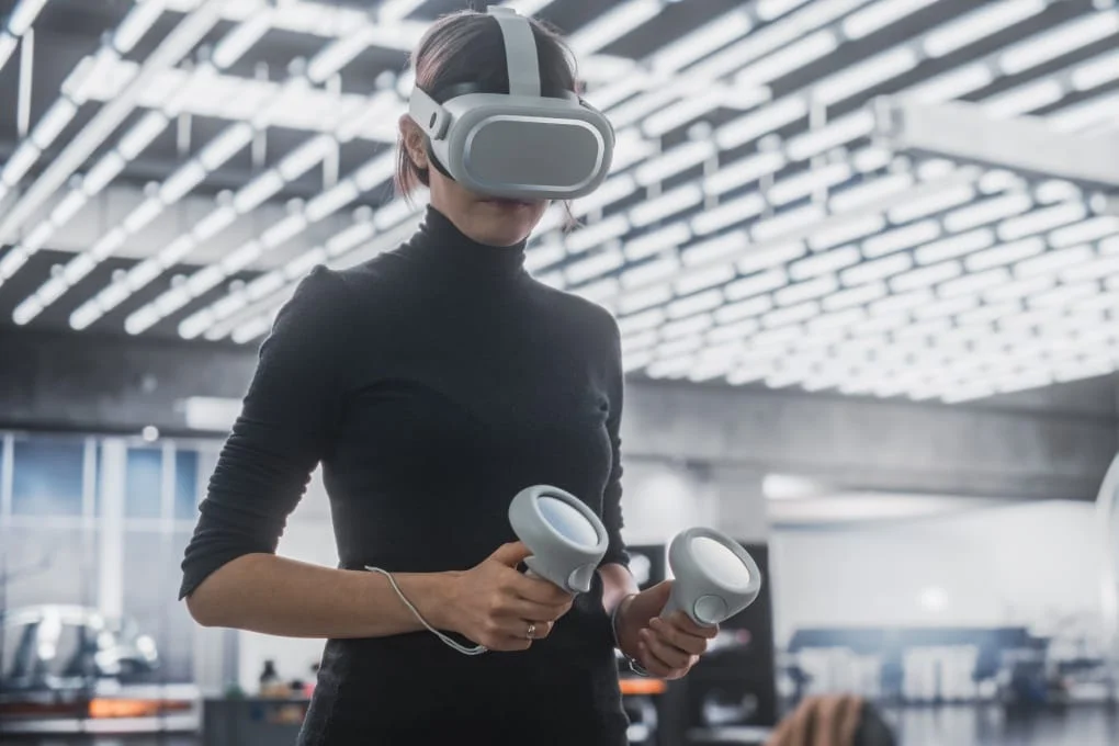 Professional using a virtual reality headset and controllers in a technology office.